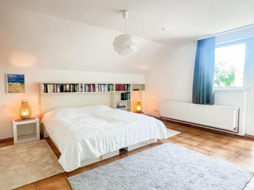 a bedroom with a white bed and a book shelf at Haus Schütz in Grömitz