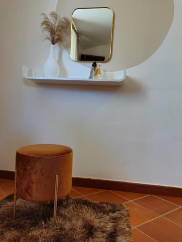 a mirror on a wall with a brown stool at Meridiana case al mare in Mattinata