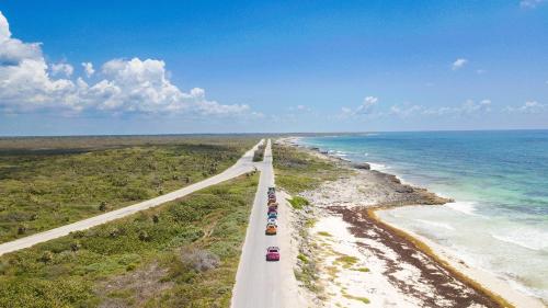 two cars driving down a road next to the ocean at The Explorean Cozumel All Inclusive in Cozumel