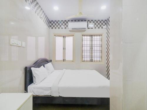 a white bedroom with a bed and a window at Hotel O Aroma Classic Near Nampally Railway station in Hyderabad
