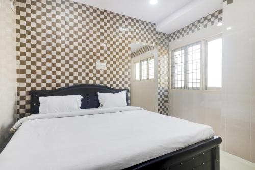 a bedroom with a bed with a checkered wall at Hotel O Aroma Classic Near Nampally Railway station in Hyderabad