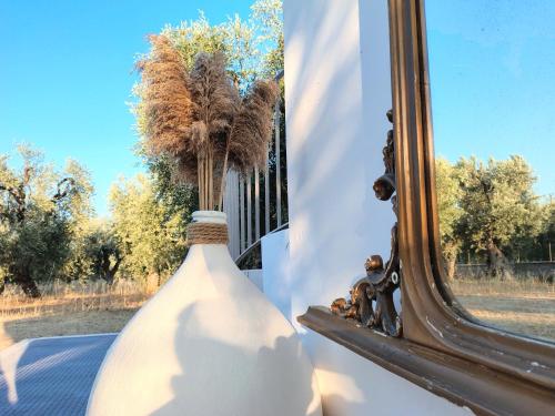 a vase with feathers in it next to a mirror at Meridiana case al mare in Mattinata