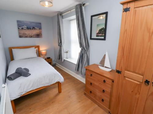 Un dormitorio con una cama y una cómoda y una ventana. en Hasting Dairy, en Seahouses