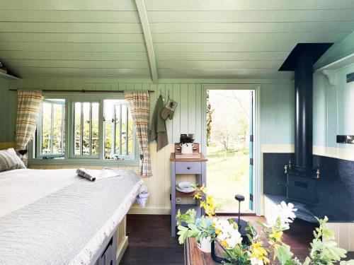 a bedroom with a bed and a large window at The Hollies Shepherds Hut by The Suffolk Cottage Collection in Sutton
