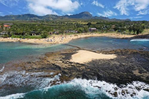an aerial view of a beach with people in the water at Hiki Moe Hale by Gather: Elegant 4BR Oasis w/ Pool & Hot Tub in Koloa