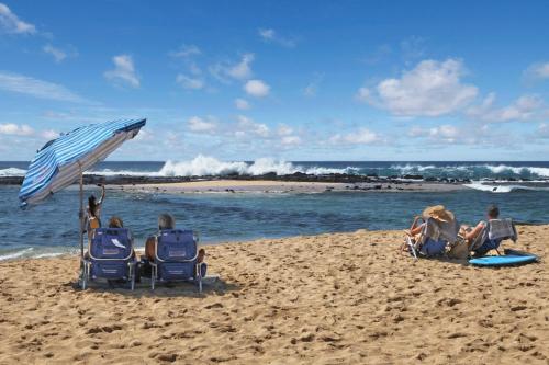a group of people sitting in chairs on a beach at Hiki Moe Hale by Gather: Elegant 4BR Oasis w/ Pool & Hot Tub in Koloa