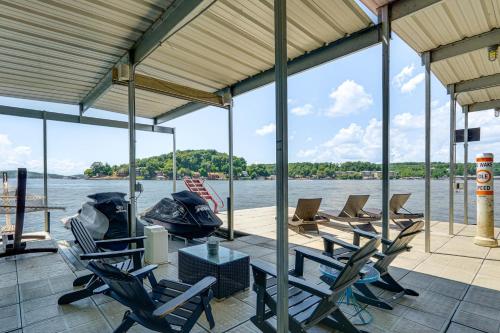a covered deck with chairs and a table and water at Hot Tub and Dock Lake Ozark Vacation Home! in Lake Ozark