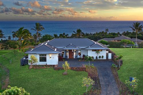 a white house with the ocean in the background at Hiki Moe Hale by Gather: Elegant 4BR Oasis w/ Pool & Hot Tub in Koloa