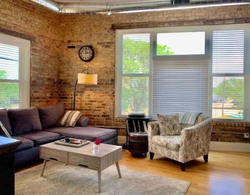 a living room with a couch and chairs and a brick wall at Romantic Gastro Loft Retreat for Two in Benton Harbor