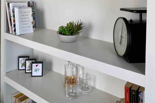 a white shelf with two glasses and a clock at Romantic Gastro Loft Retreat for Two in Benton Harbor