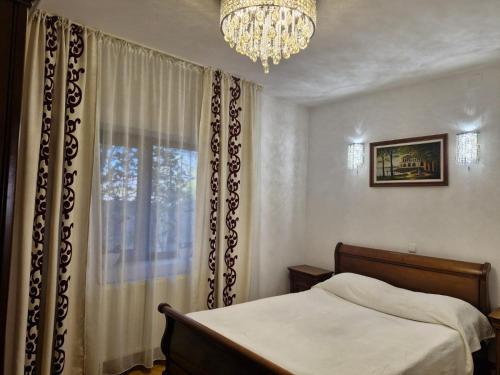 a bedroom with a bed and a chandelier and a window at Premier House in Târgu Ocna