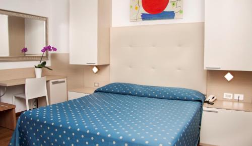 a room with a bed with a blue polka dot blanket at Hotel Ca' Serena in Sirmione