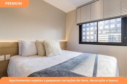 a bedroom with a bed with white sheets and a window at GO Carlos Gomes by My Way in Porto Alegre
