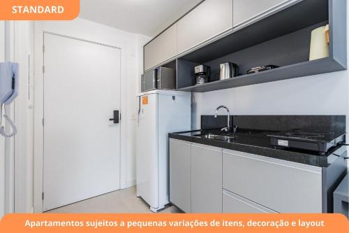a kitchen with a white refrigerator and a sink at GO Carlos Gomes by My Way in Porto Alegre