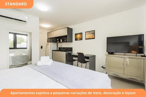 a bedroom with a large white bed and a kitchen at GO Carlos Gomes by My Way in Porto Alegre