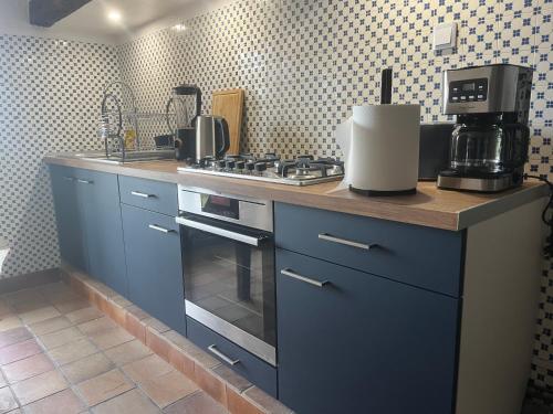 La cuisine est équipée de placards bleus et d'un four avec plaques de cuisson. dans l'établissement GITE de LAS TREILLES, à Puylaroque
