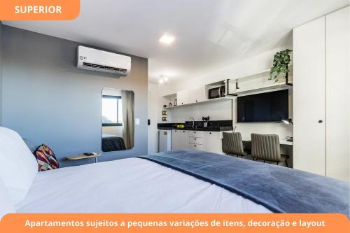 a bedroom with a bed and a kitchen with a tv at GO Carlos Gomes by My Way in Porto Alegre