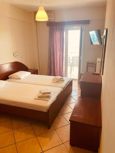a hotel room with two beds and a window at Babos Holidays in Ammoudia