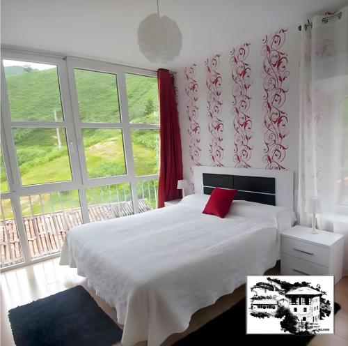 a bedroom with a white bed and a large window at El Mirador in Tudanca