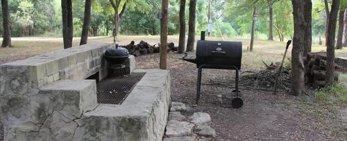 a grill and smoker in a park with trees at Mendelbaum - Loft West in Fredericksburg
