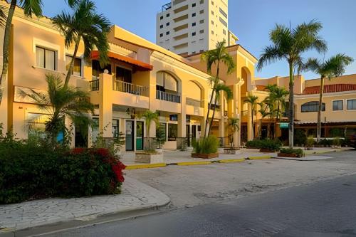 a building with palm trees next to a street at Caribbean Nature Sourrounded Refuge Apartment in Juan Dolio