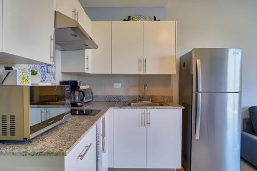 a kitchen with white cabinets and a stainless steel refrigerator at Caribbean Nature Sourrounded Refuge Apartment in Juan Dolio