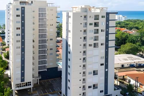 two tall white buildings with the ocean in the background at Caribbean Nature Sourrounded Refuge Apartment in Juan Dolio