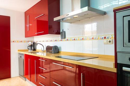a red and white kitchen with red cabinets at Casa Moraira - By Aloha Palma in Águilas