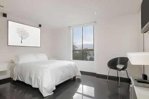 a white bedroom with a bed and a desk and a window at Santiago De Bagatela 1104 - Spacious apt Poblado in Envigado