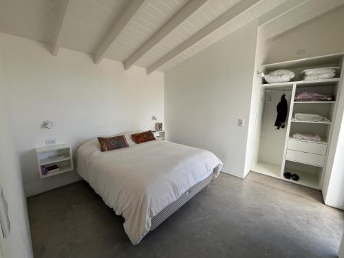 a white bedroom with a bed and shelves at Olasanta - Casa en Chapa zona Cruz del Sur para 4 PAX con vista al mar - Hola Sur in Chapadmalal