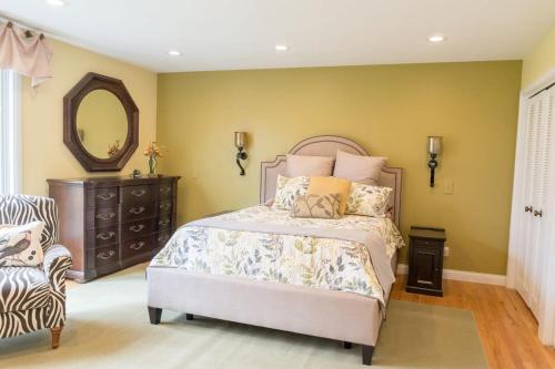 a bedroom with a bed and a mirror and a chair at Audubon Acres l pool table & outdoor dining in Benton Harbor