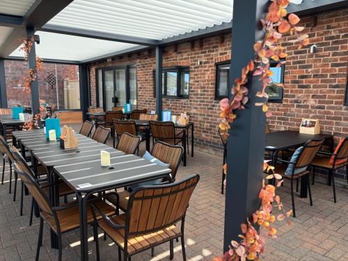 a patio with tables and chairs and a brick wall at Glamping Bell Tent - Cheshire Countryside in Church Minshull