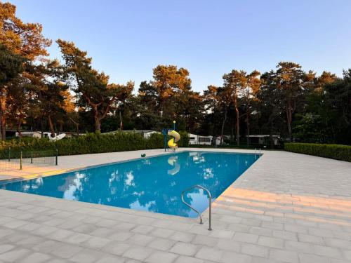 una piscina in un parco con alberi sullo sfondo di Boshuisje June - middenin de natuur op een uurtje rijden van Antwerpen en Maastricht a Balen