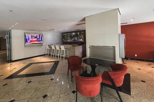 a restaurant with a bar with red chairs and a tv at Alphaville Hotel e Residence in Barueri
