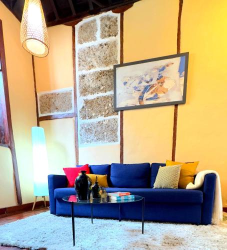 a living room with a blue couch and a table at Caletn Suites - Charming Farmhouse Retreat in Garachico, Tenerife in Garachico