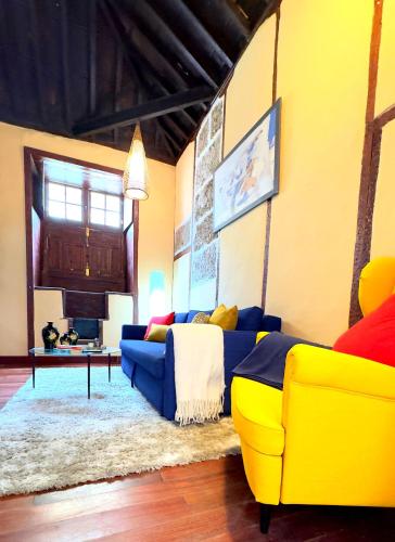 a living room with a yellow couch and a table at Caletn Suites - Charming Farmhouse Retreat in Garachico, Tenerife in Garachico