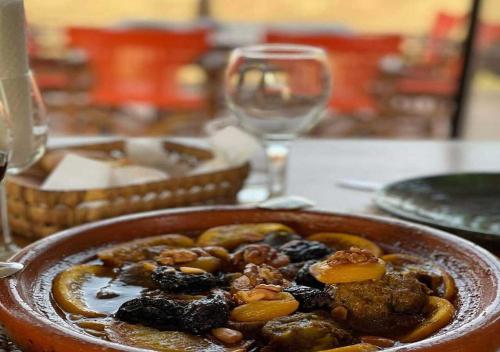 a bowl of food on a table with wine glasses at Sahara Luxurious Tented in Merzouga