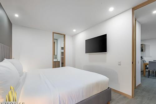 a white bedroom with a bed and a flat screen tv at Class 48 apto. 1103 - Estilo loft/vistas panorámicas in Sabaneta