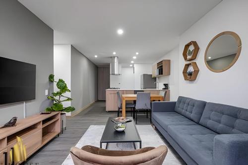 a living room with a blue couch and a table at Class 48 apto. 1103 - Estilo loft/vistas panorámicas in Sabaneta