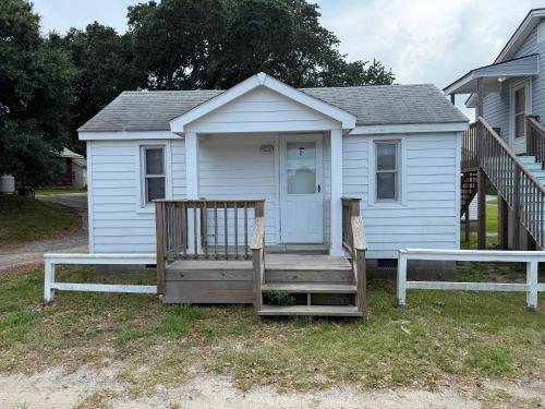 a small white house with a porch and a bench at Outer Banks Motel - Village Accommodations in Buxton