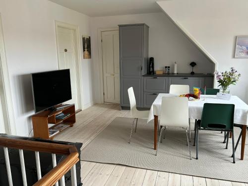 a dining room with a table and chairs and a television at Tjebberupgaard B&B in Holbæk