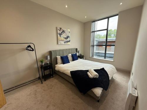 a bedroom with a bed with blue pillows and a window at Modern Spacious Leeds Penthouse in Central Station