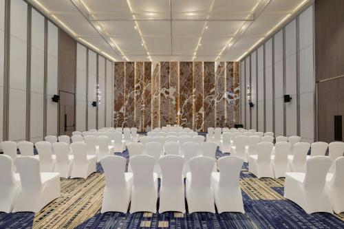 a conference room with white chairs and a stage at Le Meridien Ahmedabad in Ahmedabad