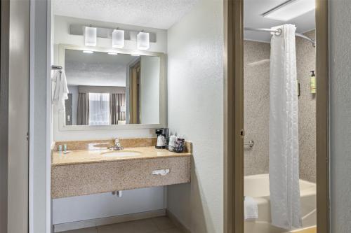 a bathroom with a sink and a mirror and a tub at Best Western Center Inn in Virginia Beach
