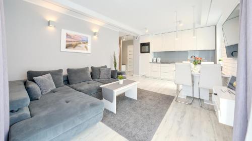 a living room with a blue couch and a kitchen at Leśne Tarasy, Sun & Snow in Dziwnówek