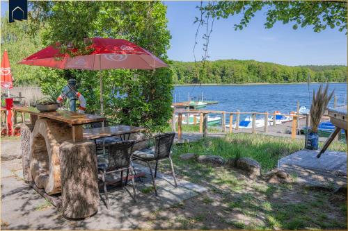 a table with an umbrella next to a lake at Waldsiedlung DHH Waldhaus 5 in Korswandt