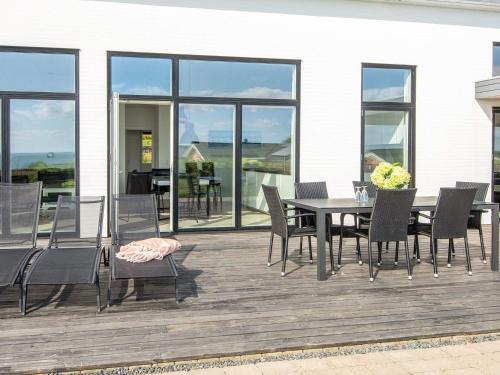 a dining table and chairs on a deck with a view of the ocean at 10 person holiday home in Sjølund-By Traum in Sjølund