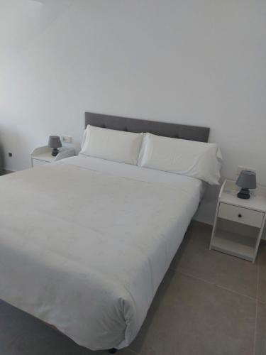 a large bed with white sheets and pillows on it at Hotel Nuevo Ondina in Begur