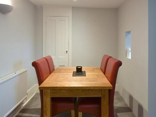 a conference room with a wooden table and red chairs at Coastguard Cottage in Ryde