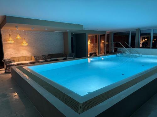 a large blue swimming pool in a building at Stay Cozy - Apartment am See mit Pool und Sauna in Bad Saarow